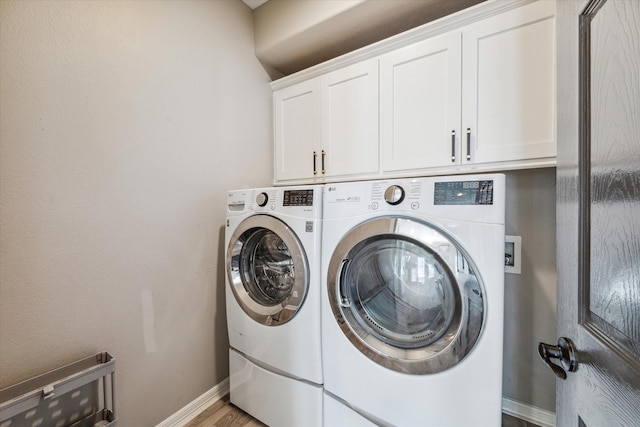 laundry area featuring washing machine and dryer, hardwood / wood-style floors, and cabinets