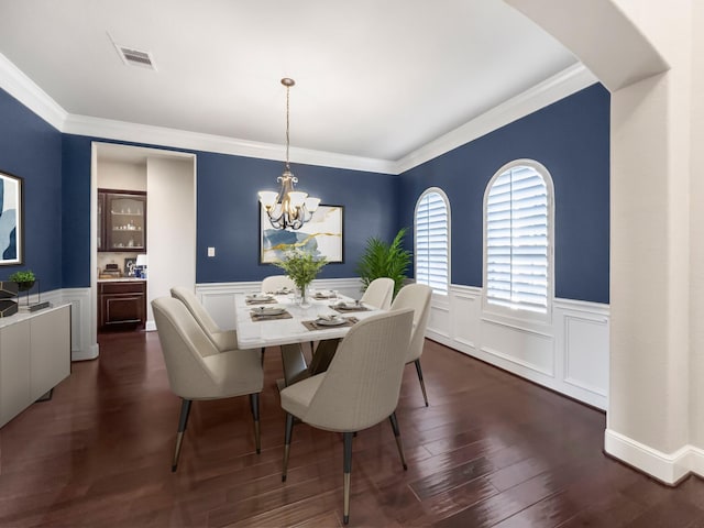 dining area featuring dark hardwood / wood-style flooring, crown molding, and an inviting chandelier