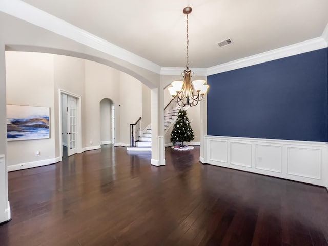 spare room with dark wood-type flooring, a notable chandelier, and ornamental molding