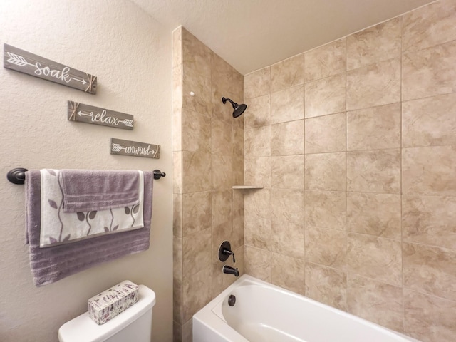 bathroom with tiled shower / bath combo and toilet