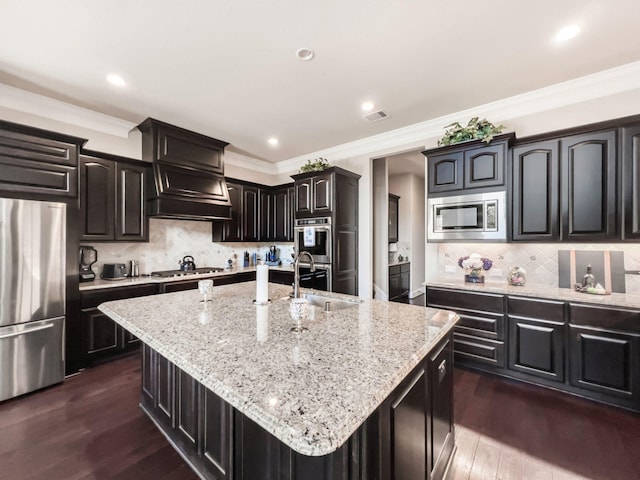 kitchen with tasteful backsplash, sink, an island with sink, and stainless steel appliances