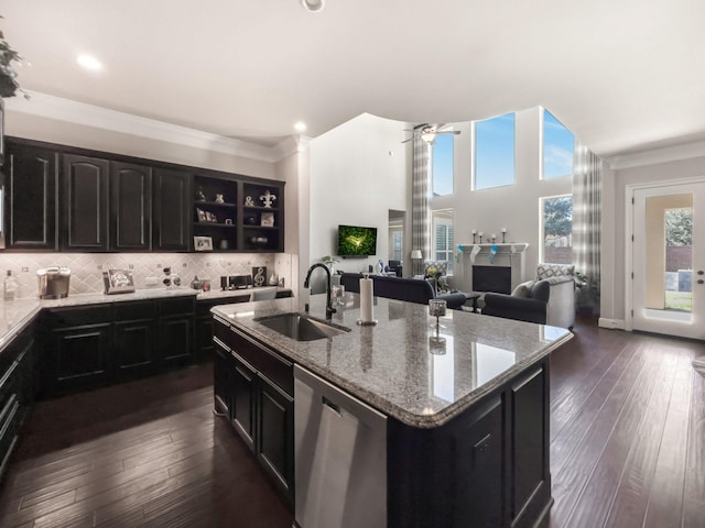 kitchen with sink, stainless steel dishwasher, dark wood-type flooring, and an island with sink