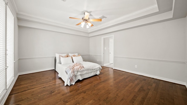 bedroom with a raised ceiling, ceiling fan, crown molding, and dark wood-type flooring