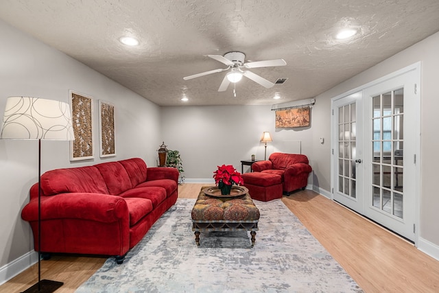 living room with hardwood / wood-style floors, french doors, a textured ceiling, and ceiling fan