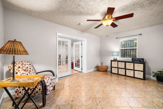 sitting room with ceiling fan, a textured ceiling, and french doors