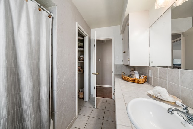 bathroom with tasteful backsplash, sink, tile patterned floors, and a shower with shower curtain