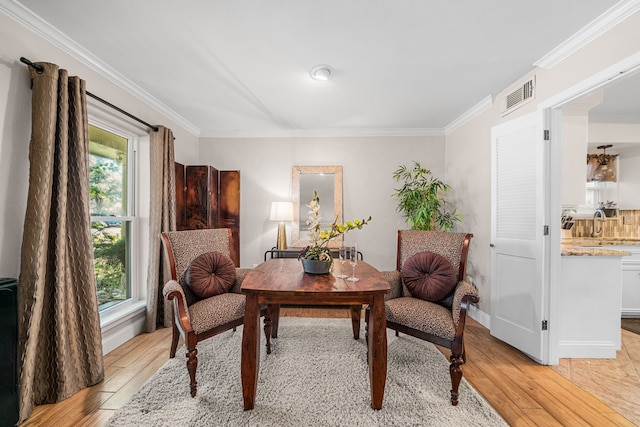 sitting room with crown molding and light hardwood / wood-style floors