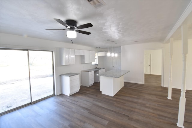 kitchen featuring dark wood-type flooring, white cabinetry, a kitchen island, and sink