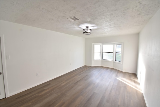 unfurnished room with a textured ceiling and dark wood-type flooring