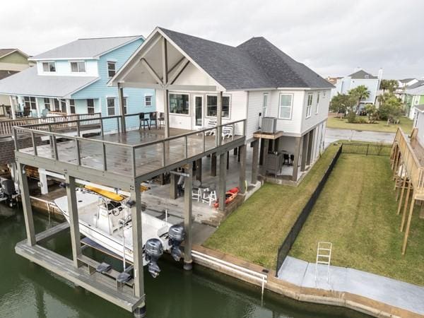 back of house featuring a patio, central AC unit, a yard, and a water view