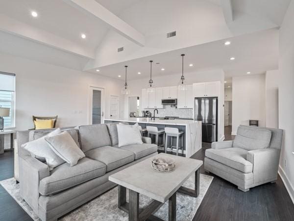 living room with sink, dark wood-type flooring, and lofted ceiling with beams