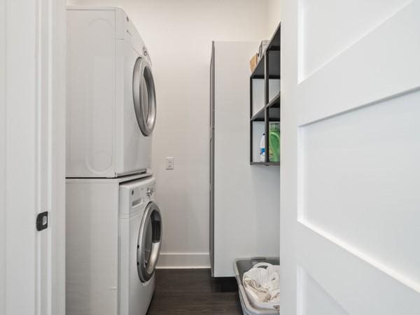 washroom with dark hardwood / wood-style floors and stacked washer and dryer