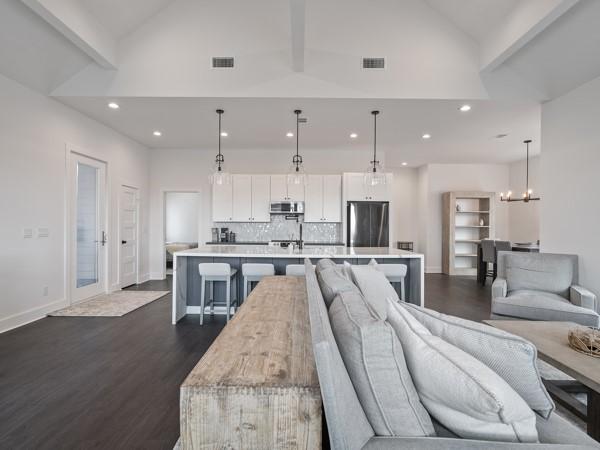 living room featuring dark hardwood / wood-style flooring, an inviting chandelier, and lofted ceiling with beams