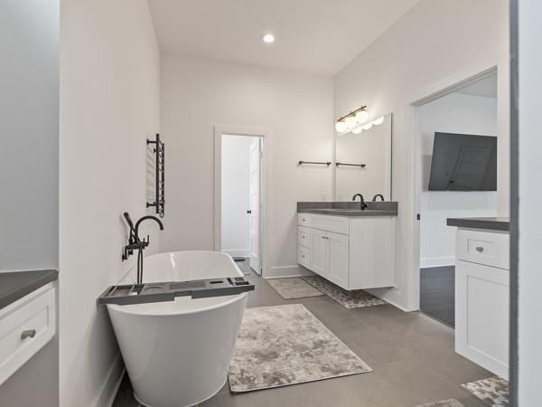 bathroom with concrete flooring, a bathtub, and vanity