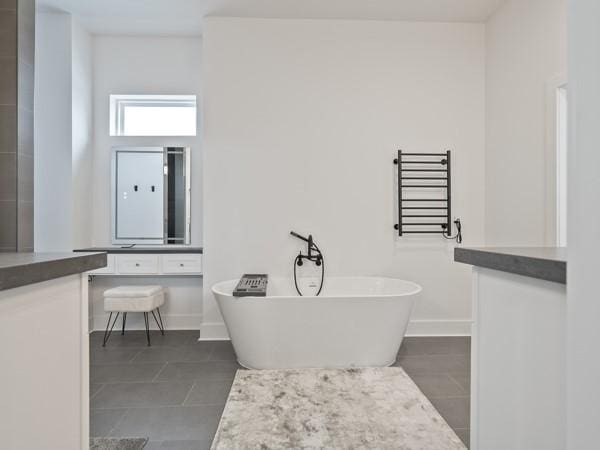 bathroom featuring tile patterned floors, a tub, vanity, and radiator