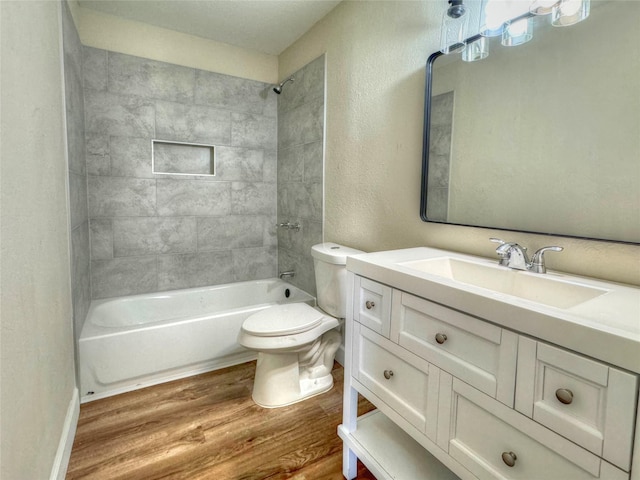 full bathroom featuring toilet, vanity, wood-type flooring, and tiled shower / bath