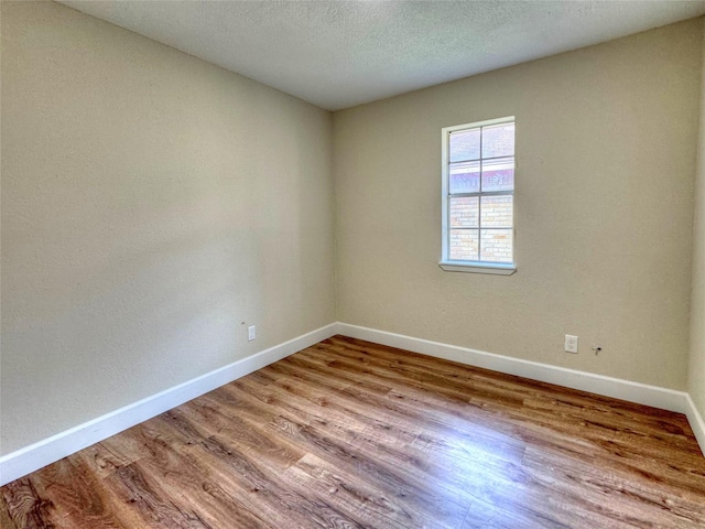 spare room with light hardwood / wood-style floors and a textured ceiling