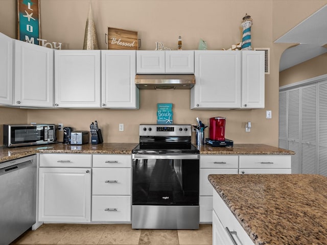 kitchen featuring white cabinets, appliances with stainless steel finishes, light tile patterned floors, and dark stone counters