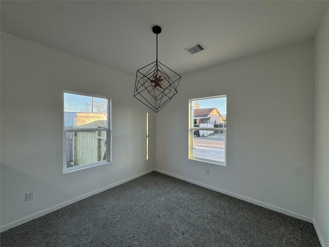 unfurnished dining area featuring plenty of natural light, dark carpet, and an inviting chandelier