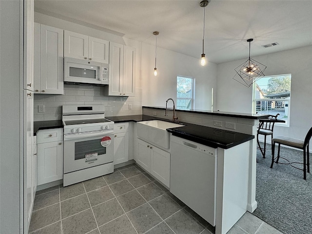 kitchen with decorative light fixtures, white cabinetry, white appliances, and kitchen peninsula