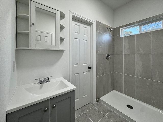 bathroom with tile patterned flooring, vanity, and tiled shower