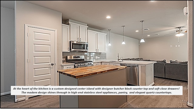 kitchen featuring kitchen peninsula, tasteful backsplash, stainless steel appliances, a kitchen island, and white cabinetry