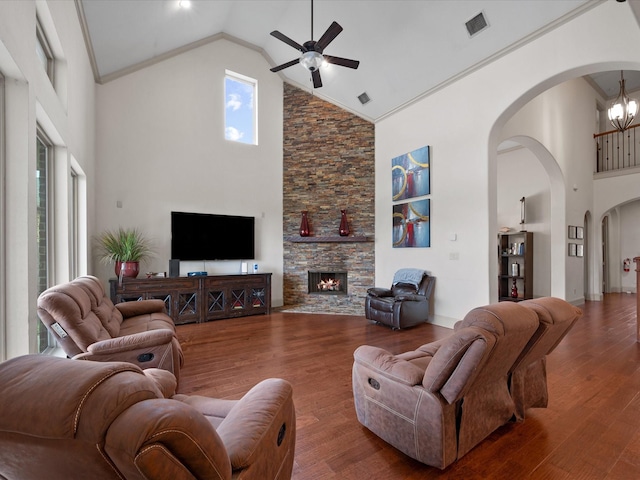 living room featuring dark hardwood / wood-style flooring, high vaulted ceiling, crown molding, a fireplace, and ceiling fan with notable chandelier