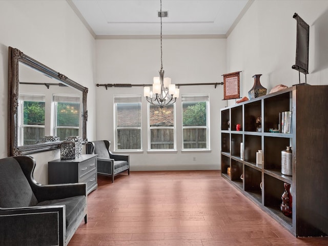 sitting room with crown molding, an inviting chandelier, and hardwood / wood-style floors