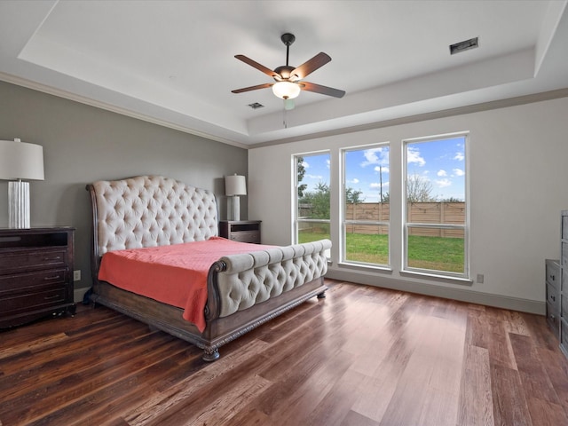 bedroom featuring a tray ceiling, ceiling fan, and dark wood-type flooring