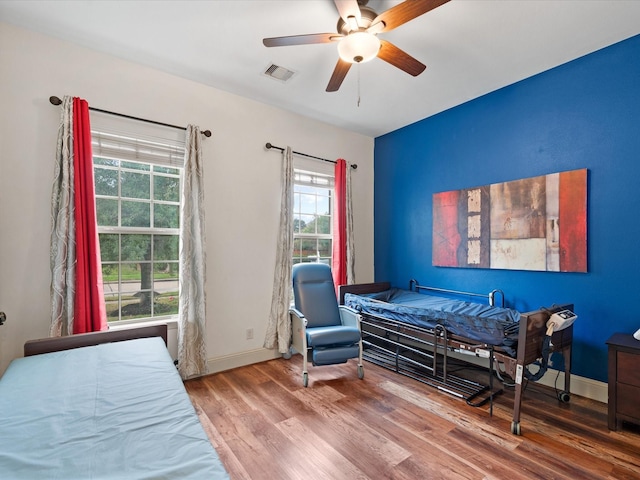 bedroom featuring hardwood / wood-style floors, ceiling fan, and multiple windows