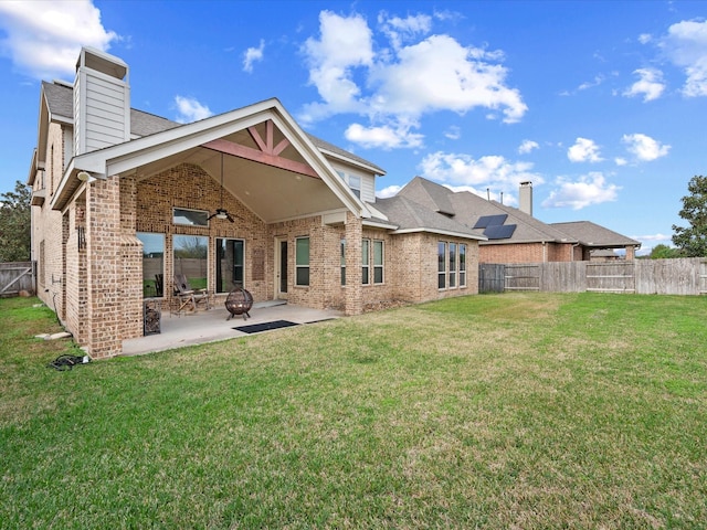 rear view of property featuring a lawn, ceiling fan, and a patio