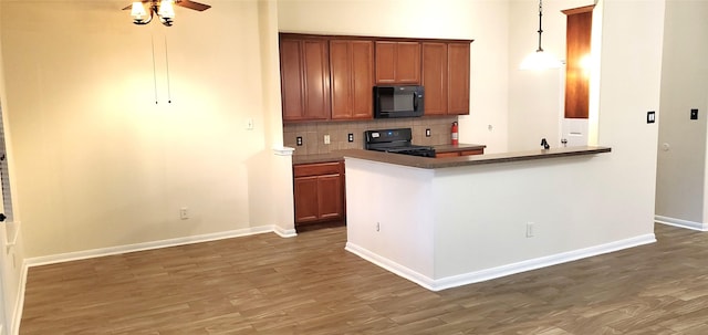 kitchen with backsplash, kitchen peninsula, hanging light fixtures, and black appliances