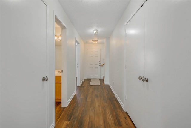 hallway with dark hardwood / wood-style flooring and a textured ceiling