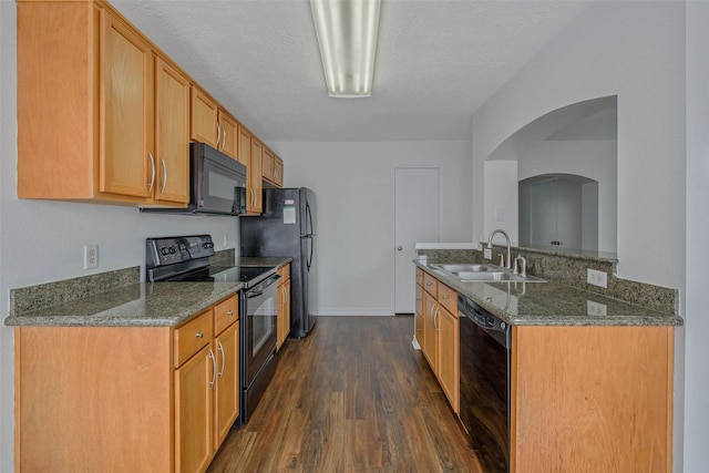 kitchen featuring dark wood-type flooring, sink, black appliances, and a textured ceiling