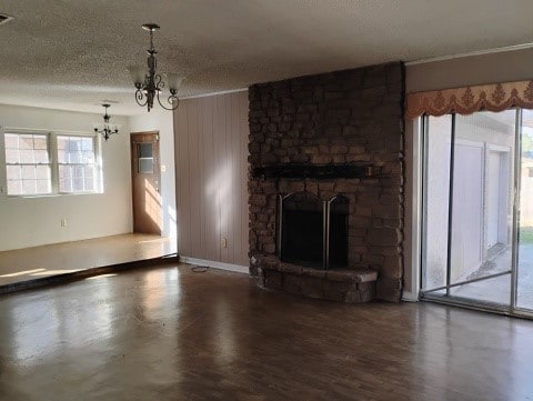 unfurnished living room featuring a textured ceiling, a fireplace, and an inviting chandelier