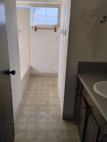 bathroom with vanity, a bath, and toilet