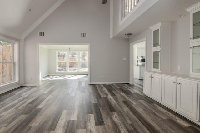 unfurnished living room featuring an inviting chandelier, crown molding, dark hardwood / wood-style floors, and high vaulted ceiling