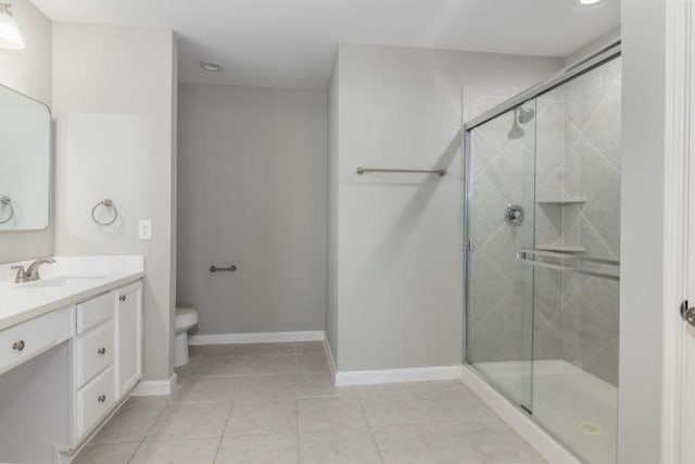 bathroom featuring tile patterned floors, vanity, toilet, and a shower with door