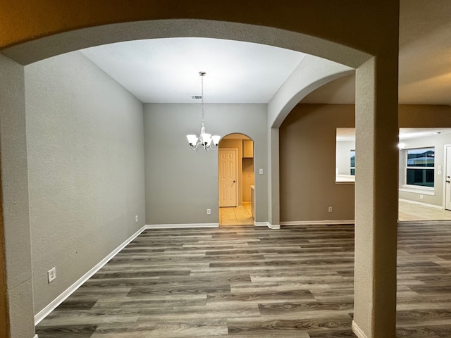 unfurnished dining area with hardwood / wood-style floors and a notable chandelier