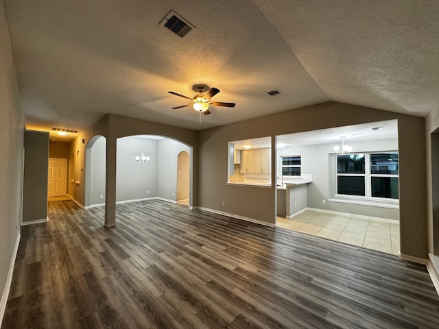 unfurnished living room with a textured ceiling, vaulted ceiling, ceiling fan with notable chandelier, and hardwood / wood-style flooring