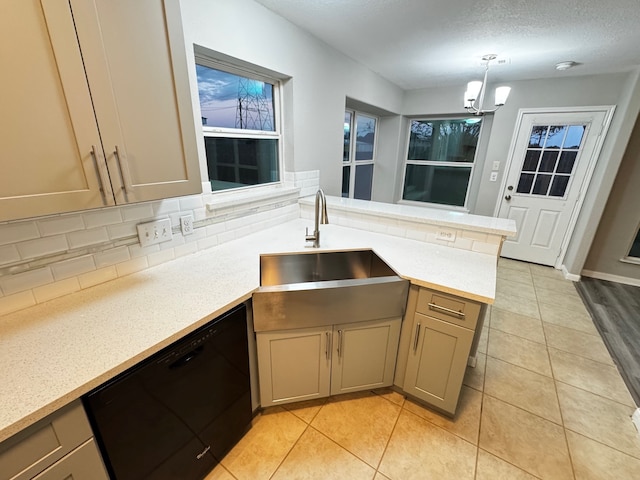 kitchen featuring kitchen peninsula, backsplash, sink, decorative light fixtures, and black dishwasher