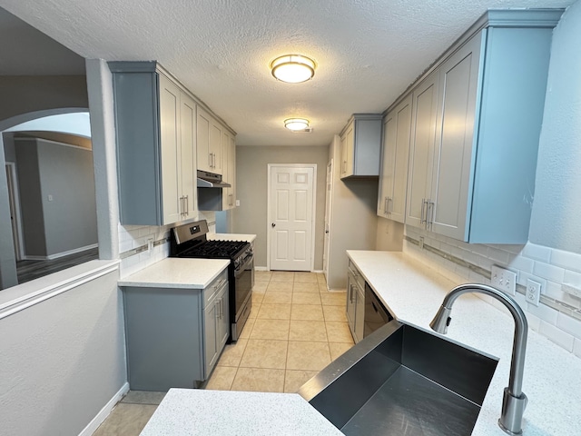 kitchen featuring a textured ceiling, decorative backsplash, gray cabinets, and stainless steel appliances