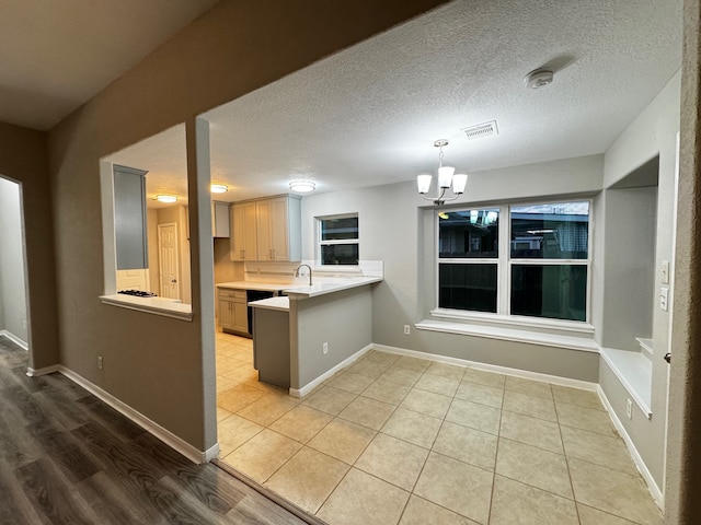 kitchen featuring light brown cabinetry, a chandelier, a textured ceiling, and light wood-type flooring