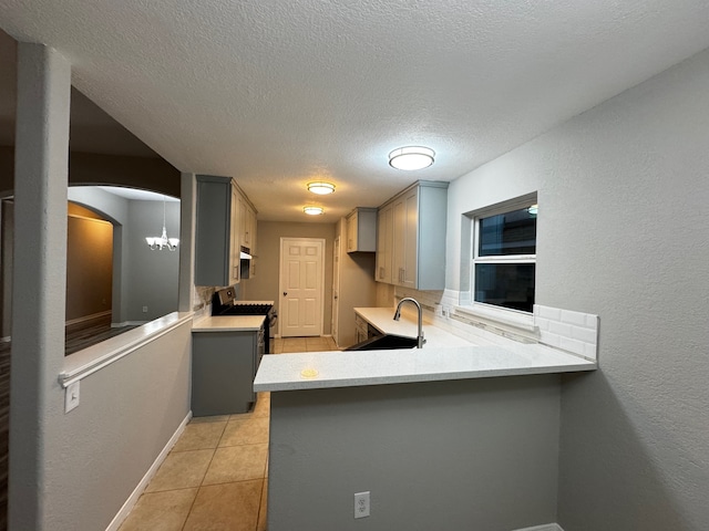 kitchen featuring kitchen peninsula, gray cabinetry, sink, and a textured ceiling