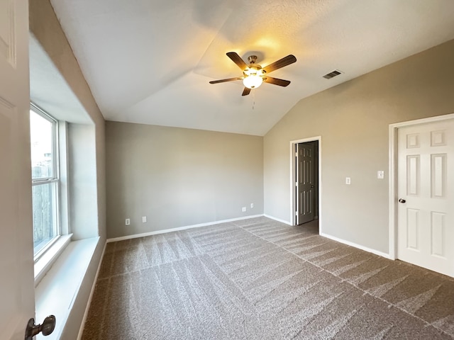 unfurnished room with a wealth of natural light, carpet, and vaulted ceiling