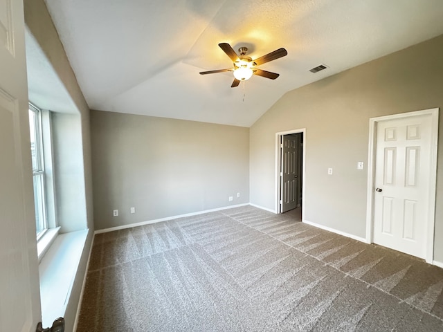 empty room featuring ceiling fan, lofted ceiling, and carpet floors