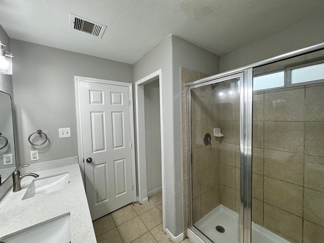 bathroom with tile patterned flooring, a shower with shower door, and a textured ceiling