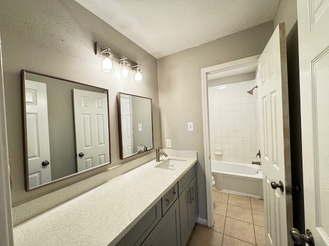 full bathroom featuring vanity, tile patterned floors, tiled shower / bath combo, toilet, and a textured ceiling