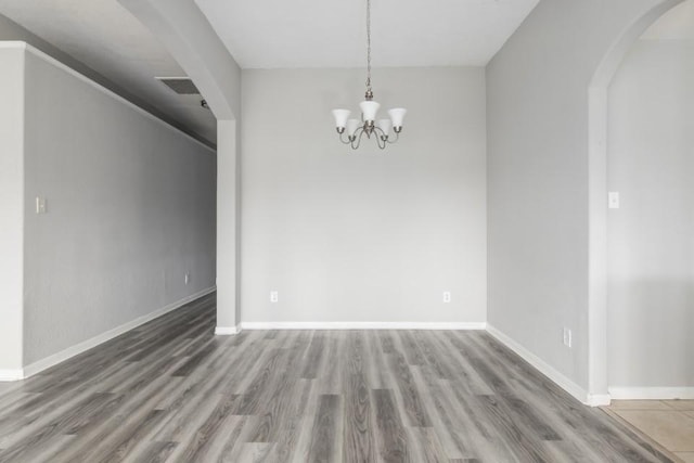 unfurnished room featuring hardwood / wood-style floors and a chandelier