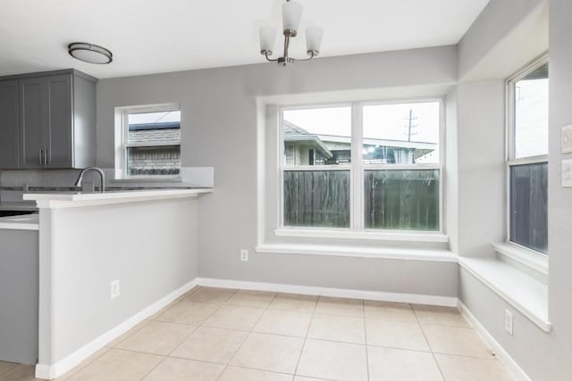 kitchen featuring light tile patterned floors, sink, gray cabinetry, decorative backsplash, and kitchen peninsula